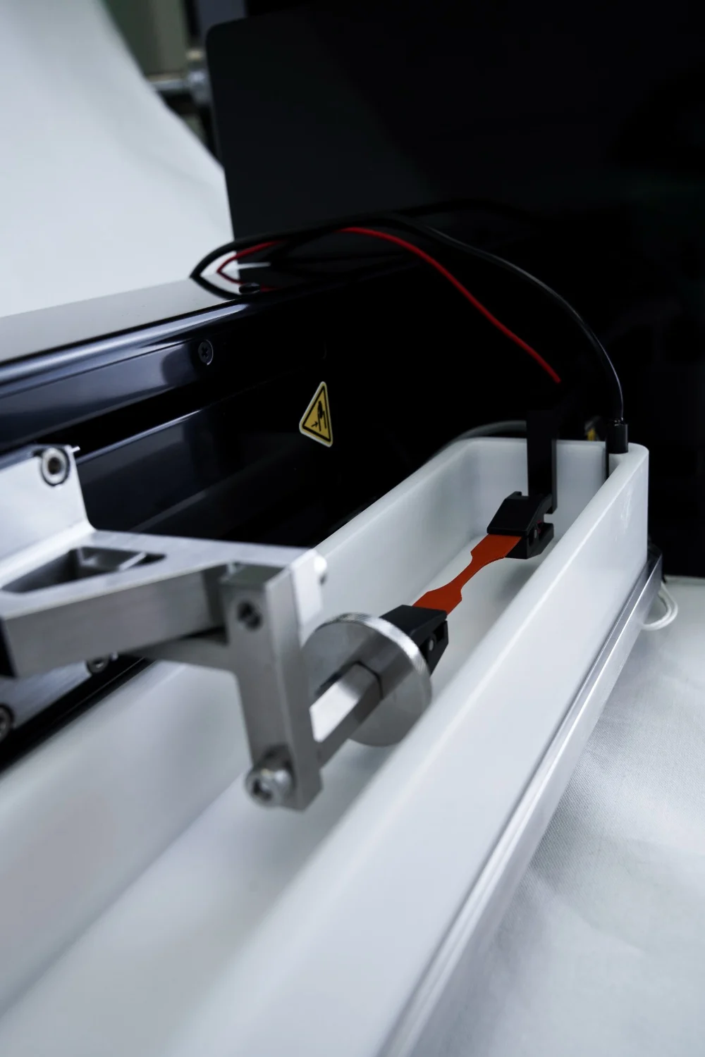 A closeup of a tensile test on the UniVert in a horizontal media bath for creep testing