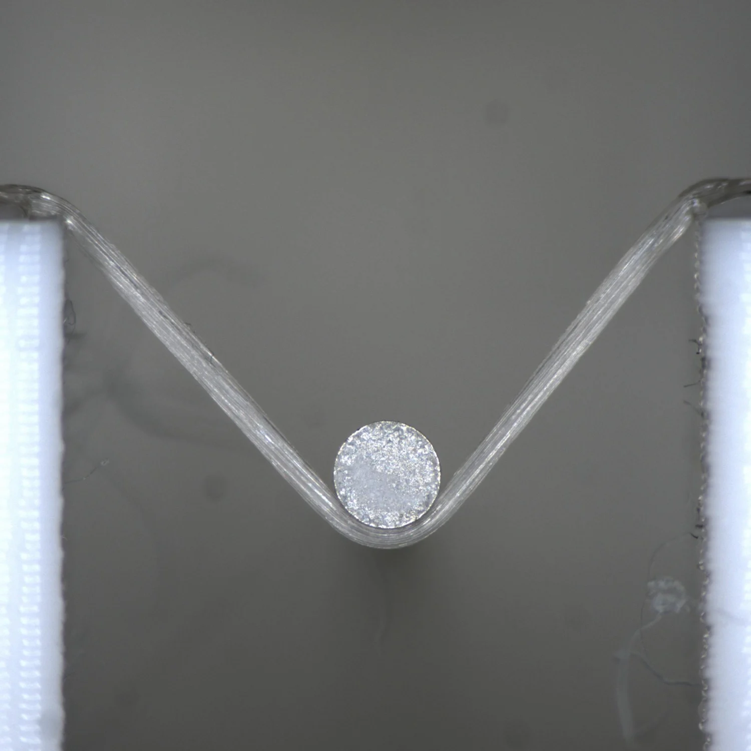 A fibre filament being tensile tested on the MicroTester