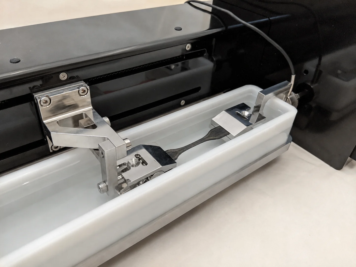 An electroactive polymer strip sample being tensile tested on the UniVert for electroactive and photothermal polymers research