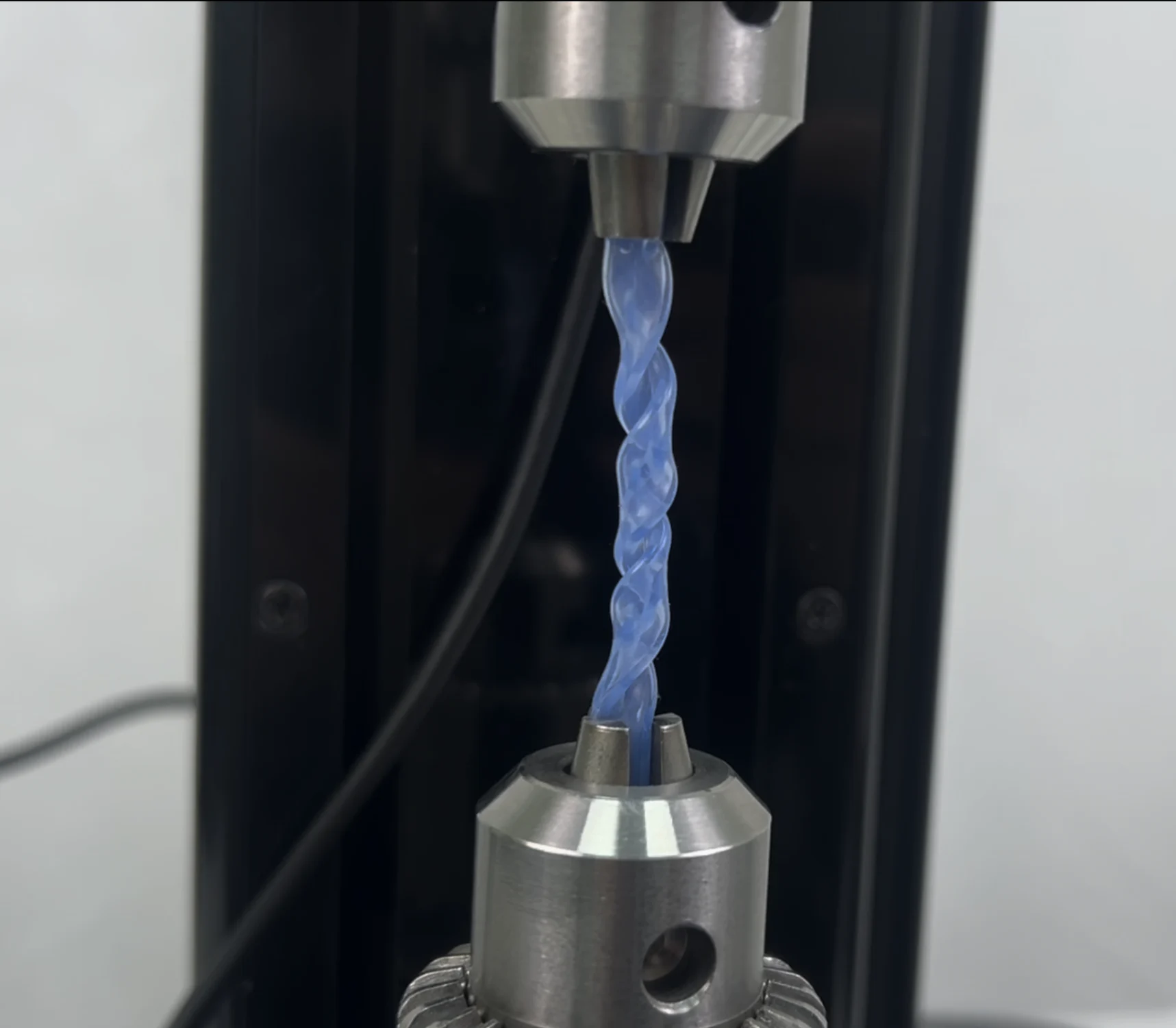 A blue polymer sample under torsion testing on the UniVert